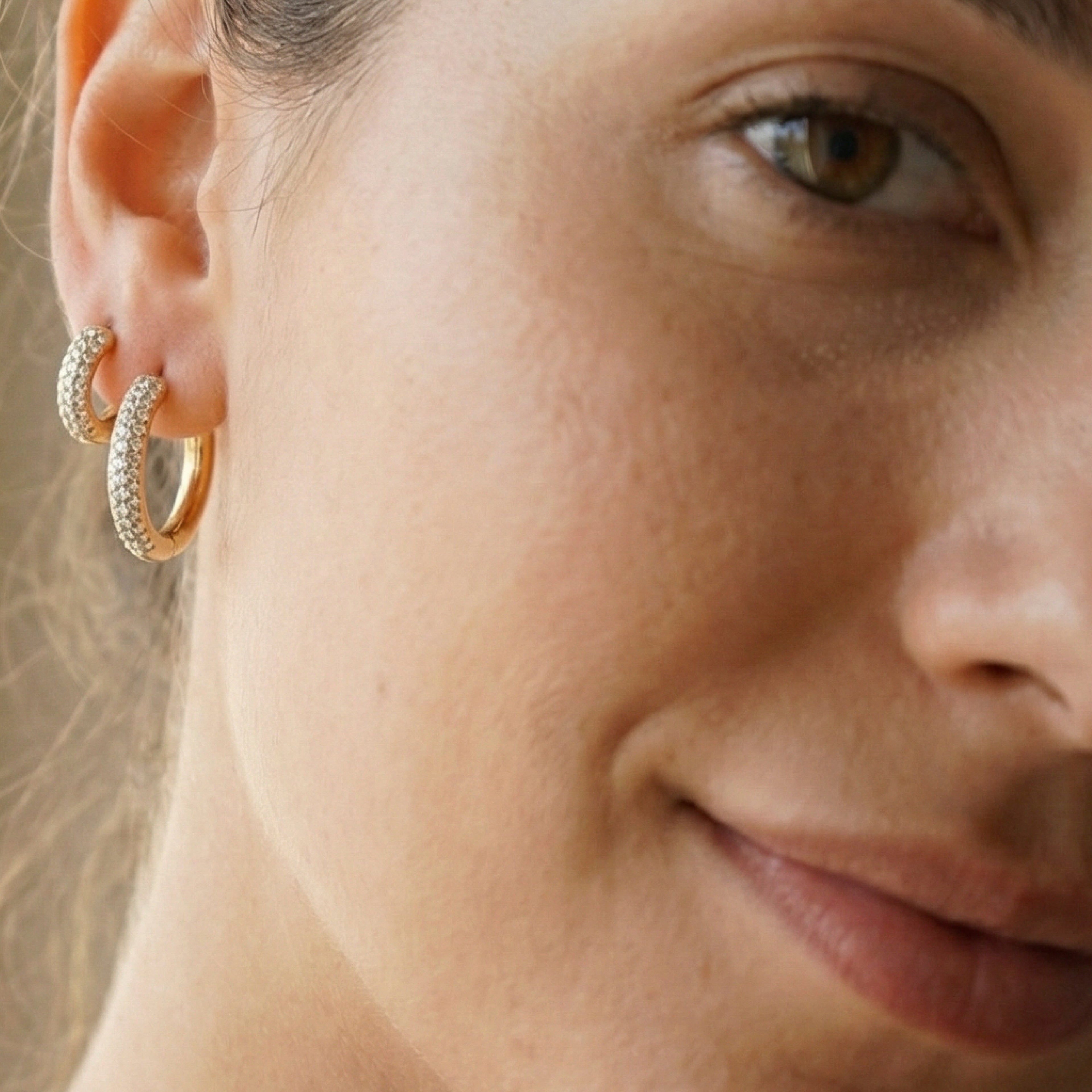 Orecchio close-up con orecchini a cerchio dorati testurizzati