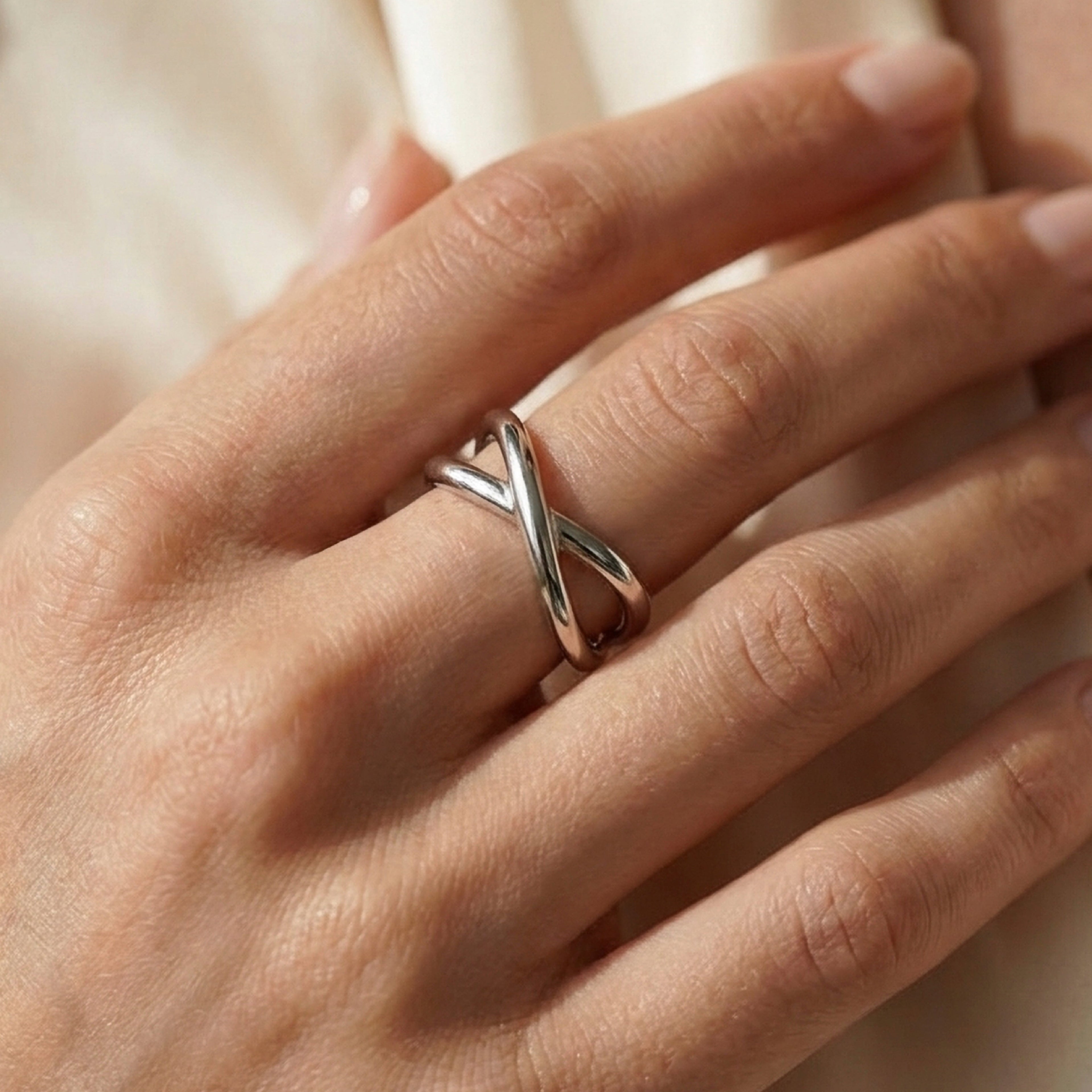 Mano con anello sottile, sfondo seta beige