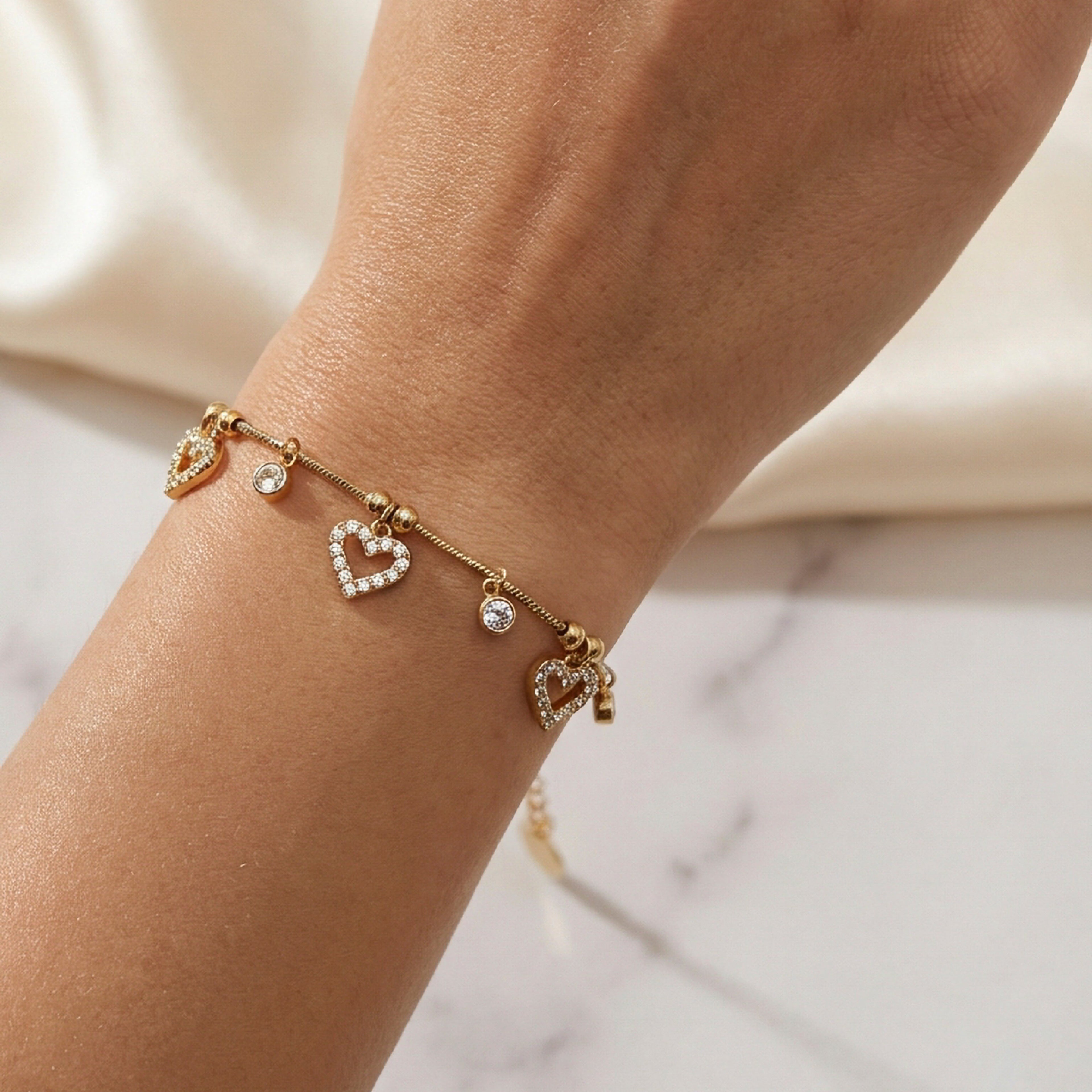 Polso con bracciale charm cuori, sfondo seta